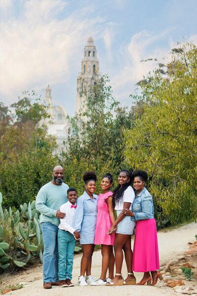 Family posing in front of bell tower at Balboa Park in San Diego