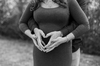 Couple celebrating first baby, maternity session, heart hands on belly