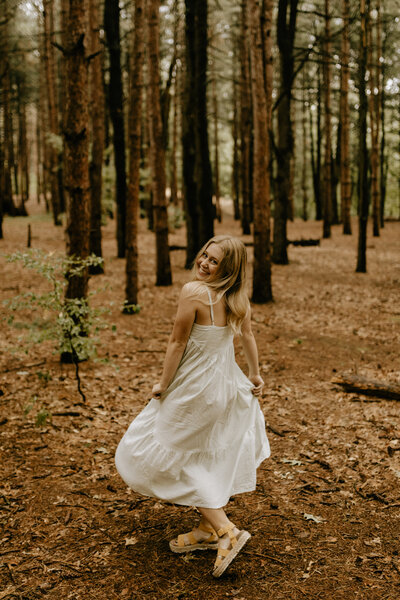 A girl spinning in her dress in a forest