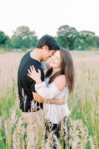 Engagement photos couple hug and laugh in field at Shawnee Mission Park