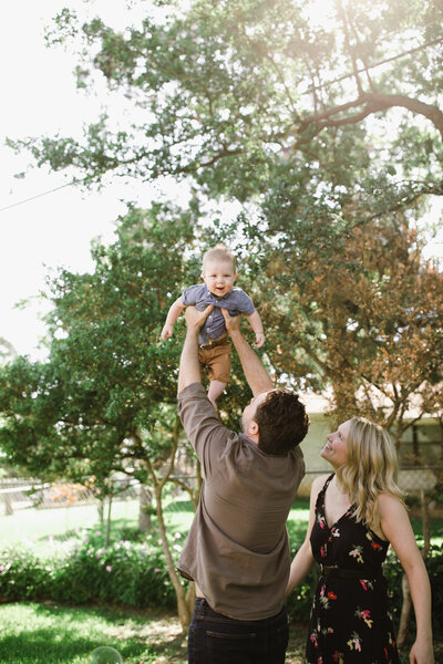 Couple holding baby in air in a park at Austin family photoshoot