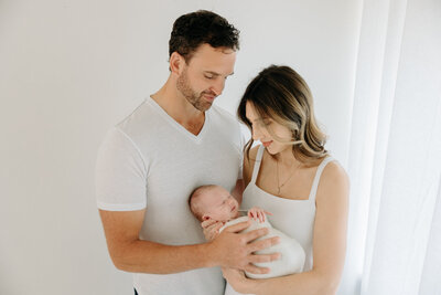 family with newborn on white bed in Pittsburgh photography studio