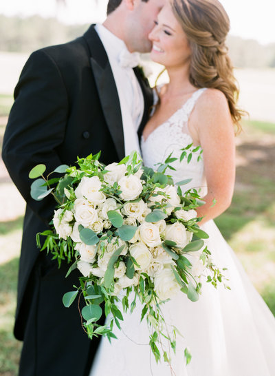 Bride with White and Ivory Floral and Greenery Bouquet with Groom in Black Tuxedo