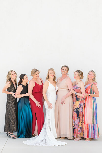 Bride and bridesmaids posing together against a white wall.