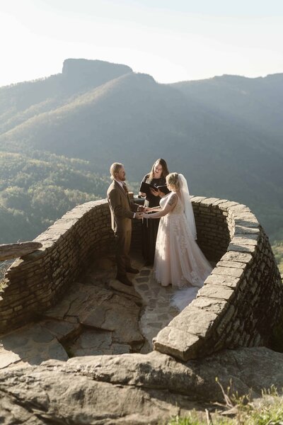 Bride and groom face each other during their ceremony overlooking beautiful mountains and a gorge