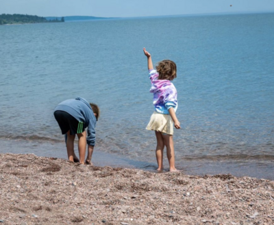 Boy and girl standing on beach throwing rocks  into Lake Superior