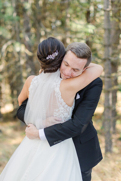 bride and groom hug in a forest of trees