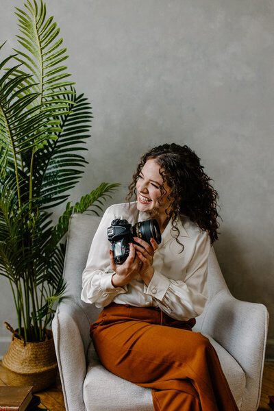 woman sitting on a couch and smiling holding a camera