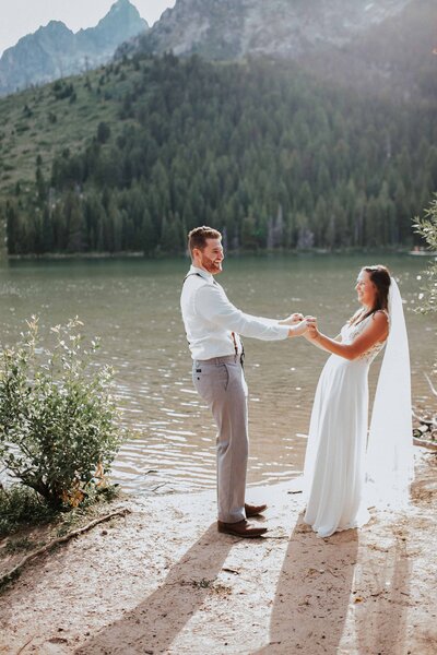 Sacramento Wedding Photographer captures bride and groom dancing along the water after forest wedding