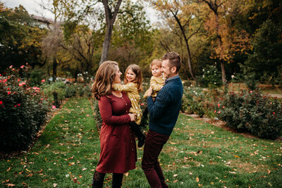 Parents holding their two young daughters while dancing in a rose garden.  Featured on page about Philadelphia photographer reviews.