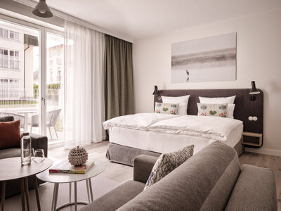 Blick auf die gemütliche Couch und das große Doppelbett im Studio  Living Apartment.
