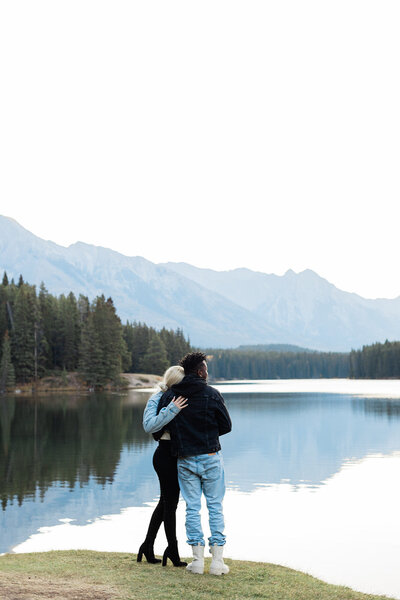 Couple hugging looking out over lake in Banff Alberta