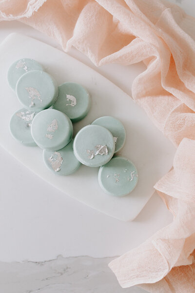 stacked light blue white chocolate dipped oreos with edible silver leaf.