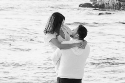 Woman being lifted up during engagement photography session in Big Sur on the beach