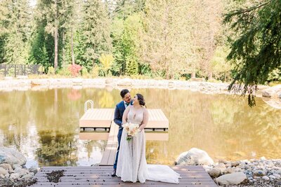 groom, standing behind bride, embracing her, with beautiful pond behind them