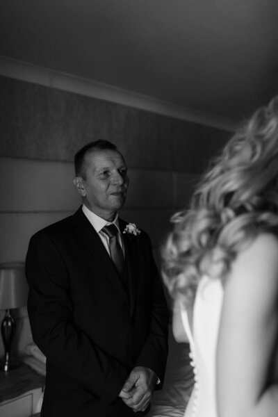 Father of the bride looks at daughter in dress