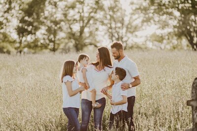 family of 5 laughing together in a field