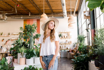 A senior girl in floppy hat in a plant shop in Lexington KY senior photo session.