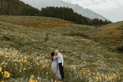 Among the wildflowers, a couple sways gently, wrapped in each other’s arms. The mountains stretch endlessly behind them, but all they see is each other. Their whispered laughter drifts into the open air, a sound as soft and fleeting as the petals at their feet.