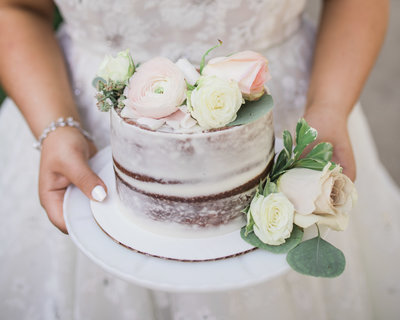 Bride hands holding Midwest Wedding Cake decorated with flowers