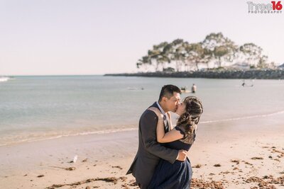 Engaged couple share a romantic kiss on Doheny State Beach in Dana Point
