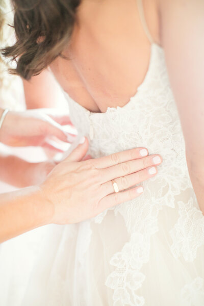 Hands fasten bride's wedding dress