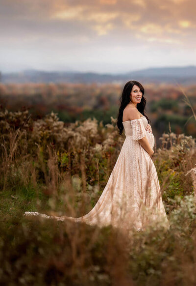 A beautiful pregnant woman poses on a mountain top near asheville for Valerie Eidson Photography during a maternity portrait session