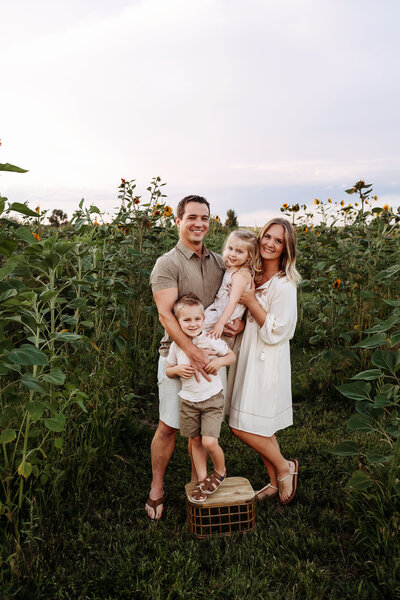 fort collins family photo session in a sunflower field together hugging