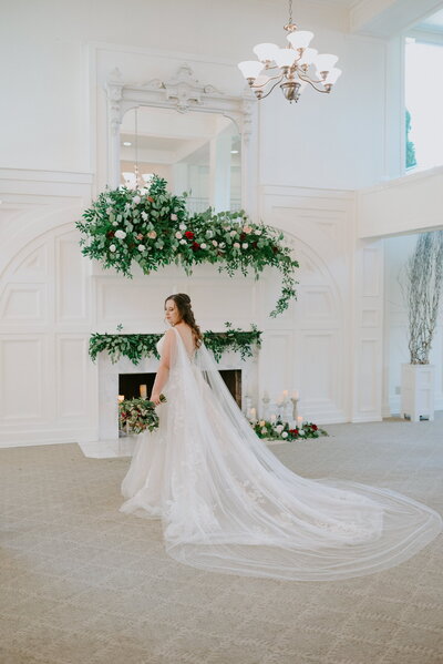 Bride standing in front of decorated fireplace in grand room