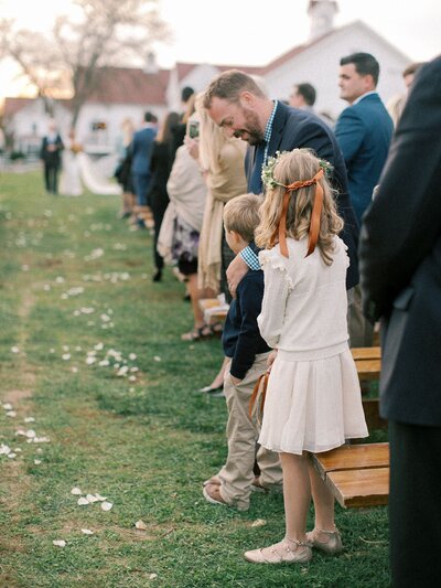 Young girl watching the bride walk down the aisle at a wedding