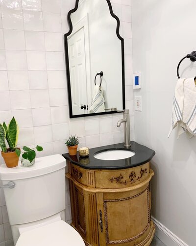 White and grey neural bathroom with wood stained vanity and black mirror