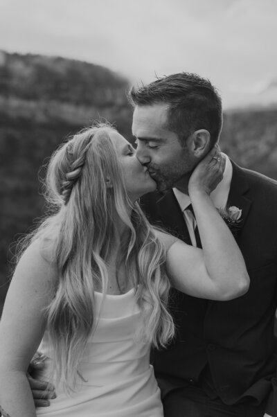 A black and white photo of a couple kissing during their elopement in Glacier National Park.