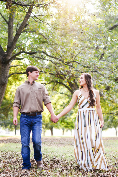 Beautiful engagement Photography: Couple holds hands and walks in a Mississippi Delta pecan orchard, MS wedding photographer