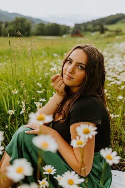 Leah sits in a field of daisies.