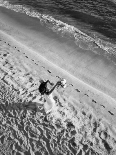 Dieses editorial Foto zeigt eine Luftaufnahme mit einer Drohne von einer tanzenden Braut am Strand.