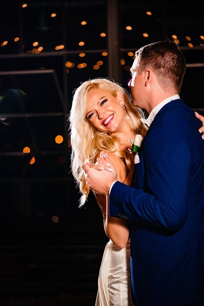Dramatic lighting with string lights and couple sharing a fun first dance at a Room with a View