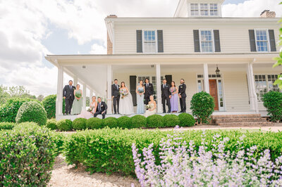 A fun wedding party in pastel colors on a timeless wrap around porch during a summer wedding at Walnut Hill while enjoying their destination wedding photos by JoLynn Photography