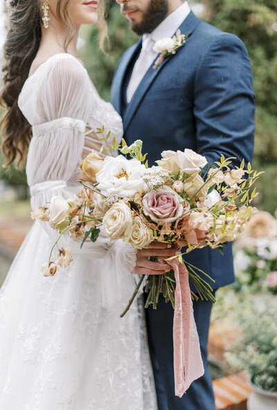 bride and groom embracing while bride holds colorful bouquet
