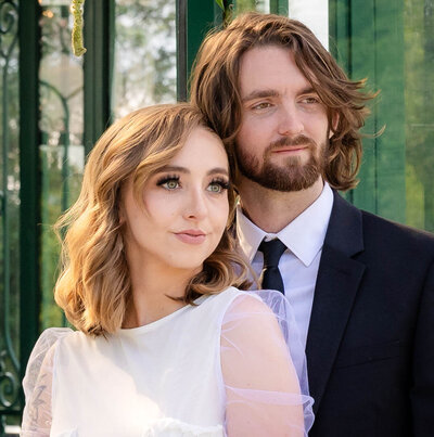 Bride and Groom in front of a elegant green solarium.