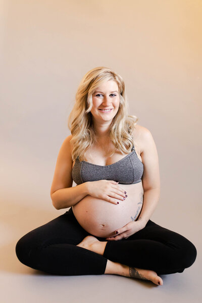 blonde lady smiling holding her baby bump