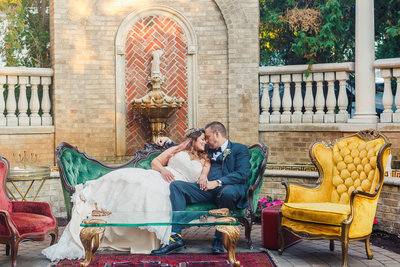 Bride and Groom Sit on a Velvet Couch Outside at their Brownstone Wedding Reception in Paterson New Jersey