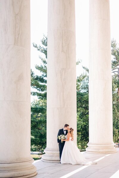 A bride and groom sharing an intimate moment between columns, captured by a Luxury Wedding Photographer.