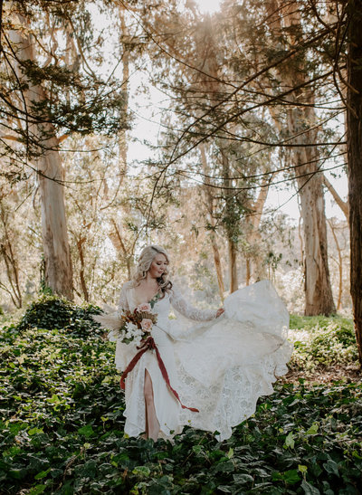 bride wearing wedding dress and holding bridal bouquet while standing in woods