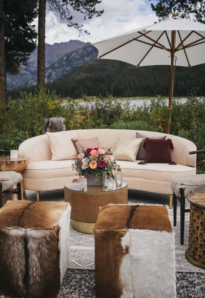 Reception seating area at dusk features a cream couch, circular coffee tables, and many cube fur stools