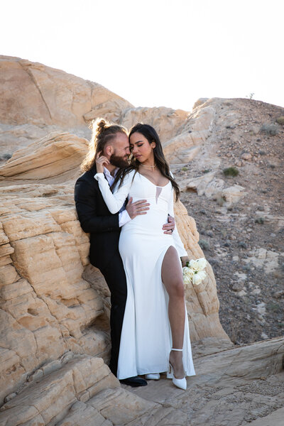 An Austin-based wedding photographer captures a loving moment of a bride and groom kissing on a picturesque rock in the desert.