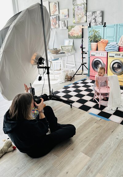 Photo of a photographer taking pictures of a toddler in the studio