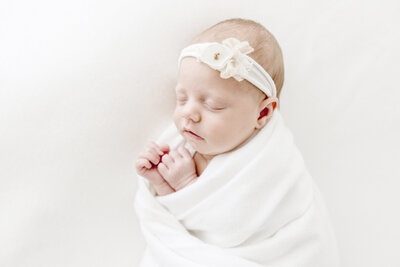 Sleeping baby in white wrap with white bow