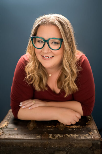 Kristine, studio manager, is pictured smiling against a blue background.