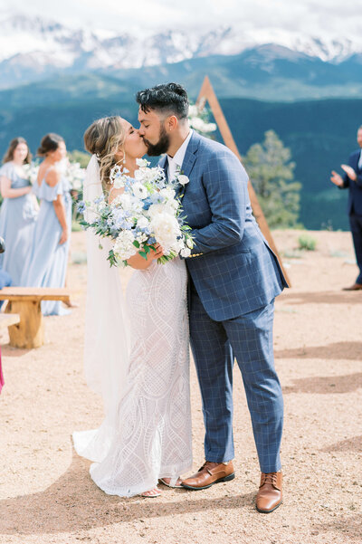 DMV wedding photographer captures an image of a bride and groom kissing at the end of the aisle during their wedding ceremony in the mountains