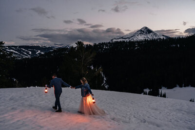 A couple carries lanterns during blue hour on their elopement day in Big Sky Montana.